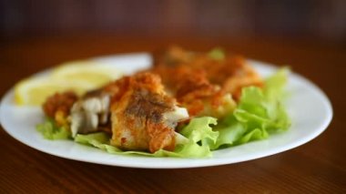 Tahta bir masada, marul ve limonlu hake balığı.