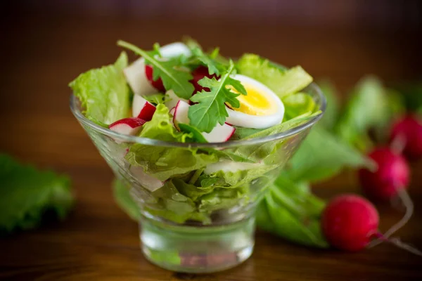Весенний салат с рукколой, вареные яйца, свежая редиска, листья салата в стеклянной миске — стоковое фото
