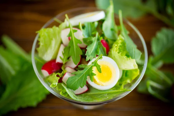 Vårsallad med ruccola, kokta ägg, färsk rädisa, salladsblad i en glasskål — Stockfoto