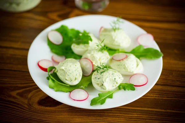 Вареные фаршированные яйца с зеленым сыром с листьями рукколы и редькой — стоковое фото