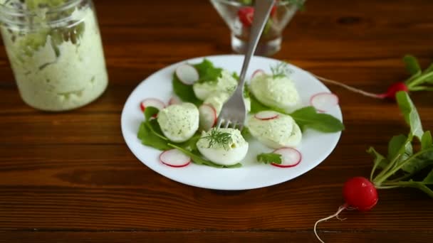 Boiled stuffed eggs with green cheese filling with arugula leaves and radish — Stock Video