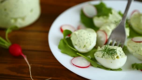 Boiled stuffed eggs with green cheese filling with arugula leaves and radish — Stock Video