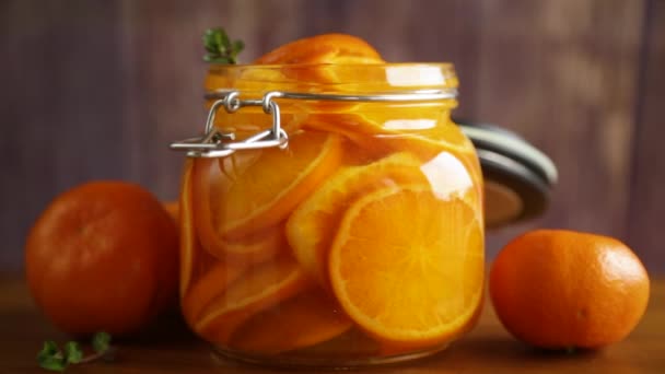 Mermelada de mandarina en un frasco de vidrio sobre una mesa de madera — Vídeo de stock