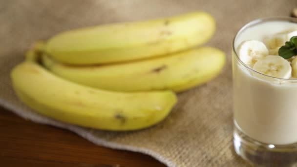 Leckerer hausgemachter Joghurt mit Bananen im Glas auf einem Holztisch — Stockvideo