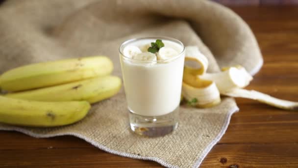 Leckerer hausgemachter Joghurt mit Bananen im Glas auf einem Holztisch — Stockvideo