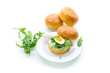 Ev yapımı peynirli çörek, taze roka ve beyaz arka planda izole edilmiş bir tabakta haşlanmış yumurta.