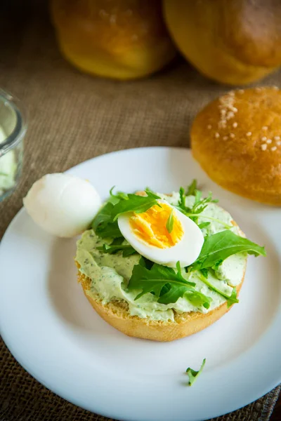 自家製パン チーズスプレッド 新鮮なアルグラと木製のテーブルの上にプレートにゆで卵 — ストック写真