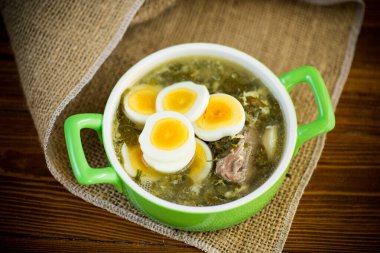 Yeşil doru taze bahar organik çorbası ve ahşap masada bir tabakta yumurta.