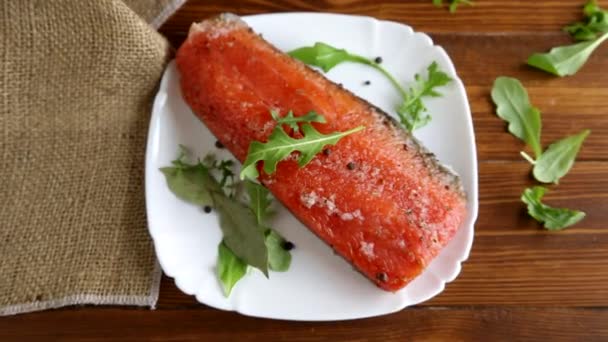 Кусок соленой красной рыбы с различными приправами и травами в тарелке — стоковое видео