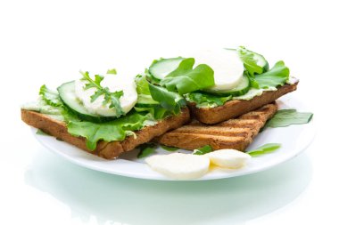 Salata yapraklı kızarmış ekmek, peynir sosu ve beyaz arka planda izole edilmiş bir tabakta mozzarella.
