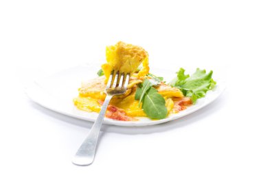 Beyaz arka planda izole edilmiş bir tabakta sebzeli omlet ve roka.