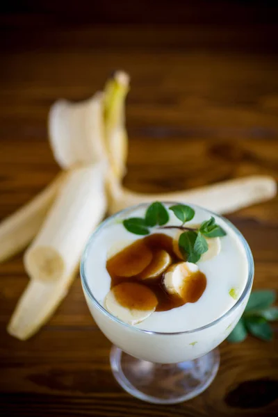 自制甜酸奶 在木桌上的玻璃碗里放上成熟的香蕉和焦糖片 — 图库照片