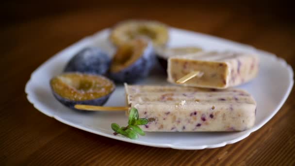 Plum sweet homemade ice cream on a stick with slices of plum inside, in a plate — Stock Video