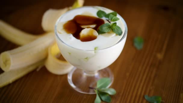 Yaourt sucré fait maison avec des tranches de banane mûre et de caramel dans un bol en verre — Video