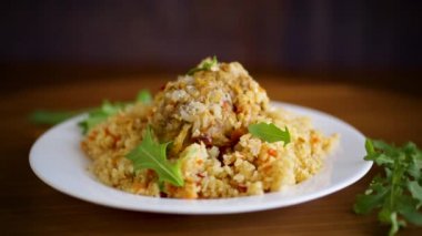 Kaynamış bulgur, sebze ve köftelerle dolu bir tabakta inliyor.