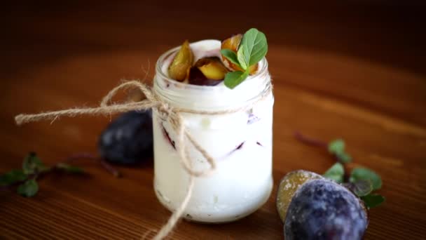 Yaourt sucré fait maison avec des tranches de prunes mûres dans un verre — Video