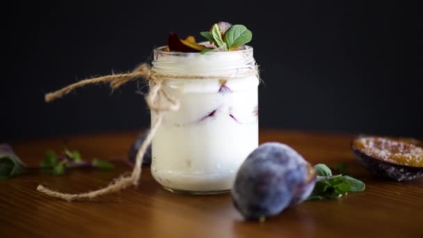 Domácí sladký jogurt s plátky zralých švestek ve sklenici