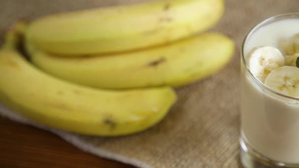 Leckerer hausgemachter Joghurt mit Bananen im Glas auf einem Holztisch — Stockvideo