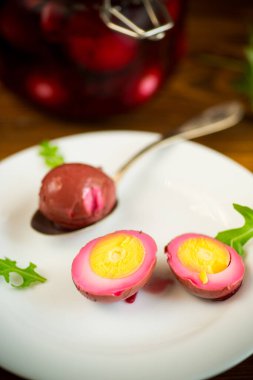 Pancar salamurasında marine edilmiş tavuk yumurtaları ahşap bir masada bir tabakta.