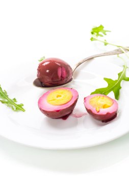 Beyaz arka planda izole edilmiş bir tabakta pancar salamurasında marine edilmiş tavuk yumurtası.