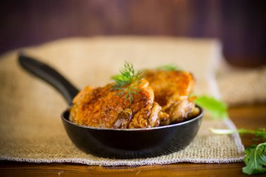 Tavuğun bacakları tavada kızarır, ahşap bir masada.