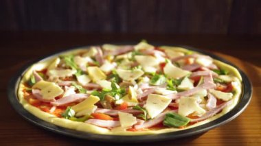 Tahta bir masanın üzerinde metal bir form doldurulmuş çiğ pizza.