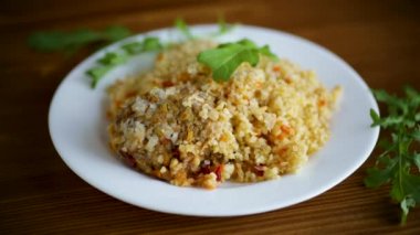 Kaynamış bulgur, sebze ve köftelerle dolu bir tabakta inliyor.