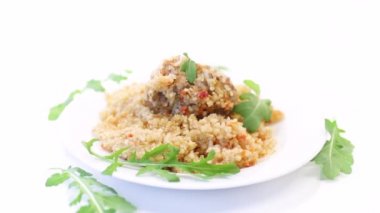 Kaynamış bulgur, sebze ve köftelerle dolu bir tabakta inliyor.
