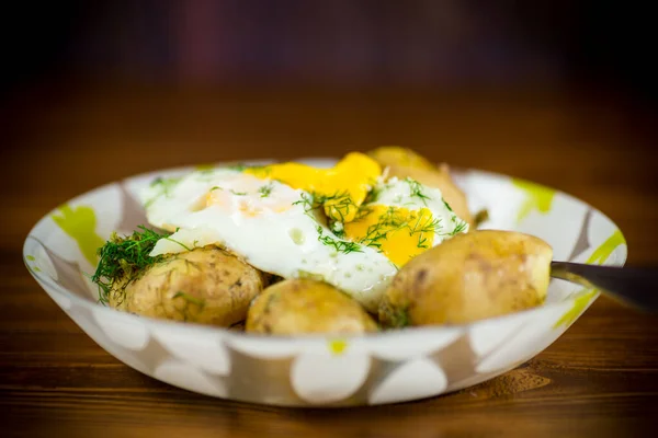 boiled early potatoes with fried egg and dill in a plate
