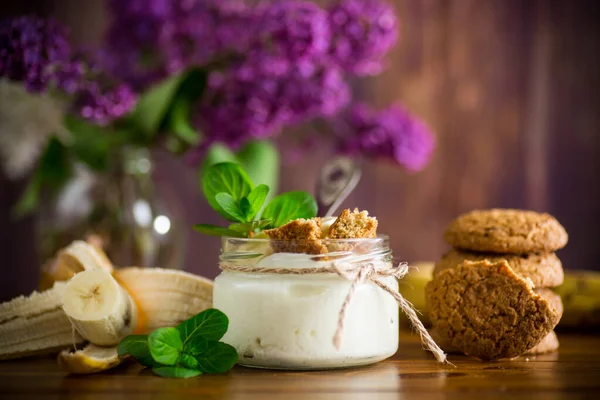 sweet homemade yogurt with fresh bananas and slices of oatmeal cookies in a glass jar