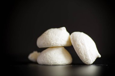 Siyah arka planda izole edilmiş çuval bezi masa örtüsü olan tatlı, lezzetli beyaz kremalar.