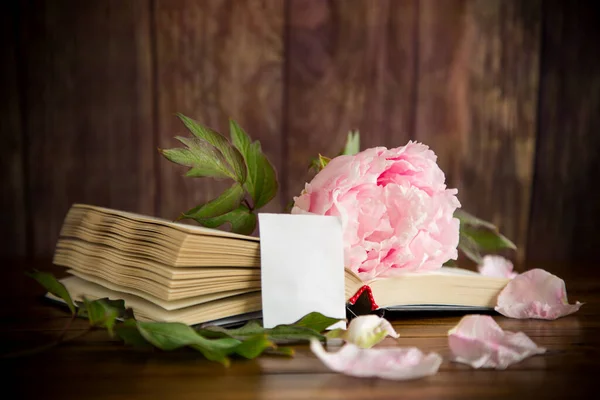 peony pink beautiful flower, book, empty card on a wooden table