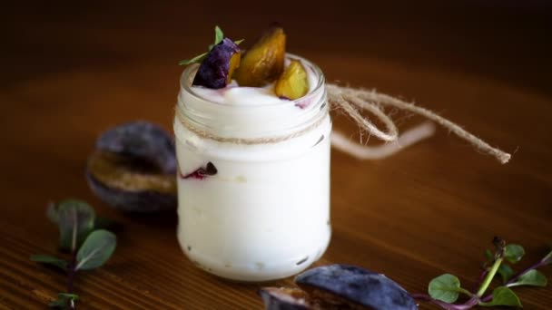 Yogur dulce casero con rodajas de ciruelas maduras en un vaso — Vídeos de Stock