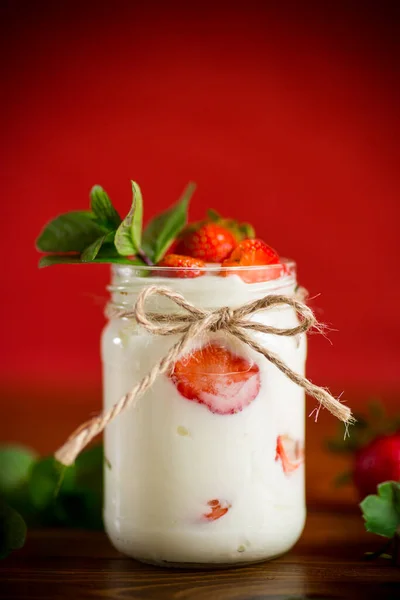 甘い自家製ヨーグルトに熟した新鮮なイチゴを木のテーブルの上の瓶に入れ — ストック写真
