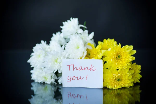 bouquet of white chrysanthemums with a greeting card for mom on a black background