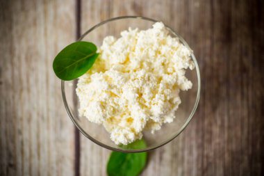 Taze organik süzme peynir ahşap bir masada cam bir kasede.