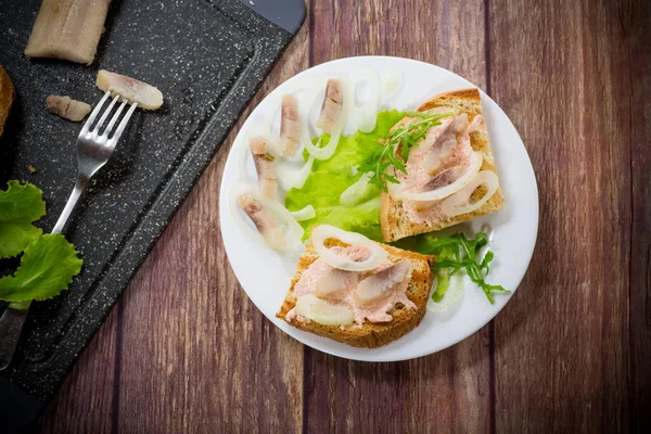 Sándwich con ensalada, arenque y hierbas con cebolla en un plato —  Fotos de Stock