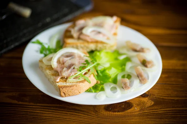Бутерброд з салатом, оселедцем і травами з цибулею в тарілці — стокове фото
