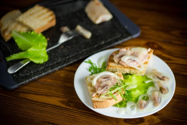 Бутерброд з салатом, оселедцем і травами з цибулею в тарілці — стокове фото