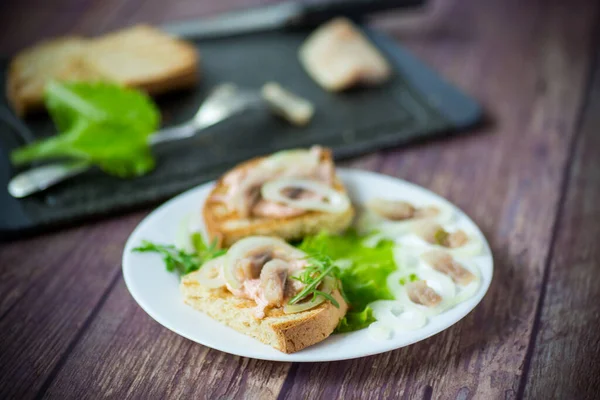 Broodje met salade, haring en kruiden met uien in een bord — Stockfoto