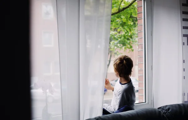 Мальчик, сидящий у окна — стоковое фото