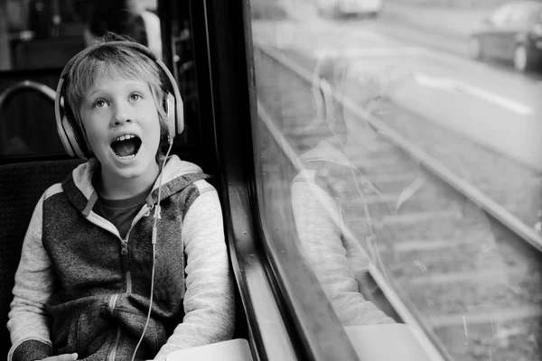 Мальчик в наушниках в поезде — стоковое фото