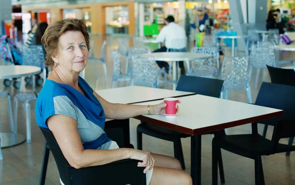 Portret van mooie 70 jaar oude vrouw zitten in de luchthaven — Stockfoto