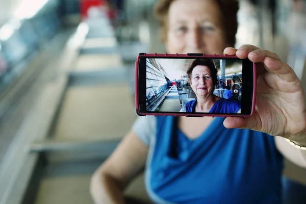 Portret van mooie 70 jaar oude vrouw zitten in de luchthaven — Stockfoto