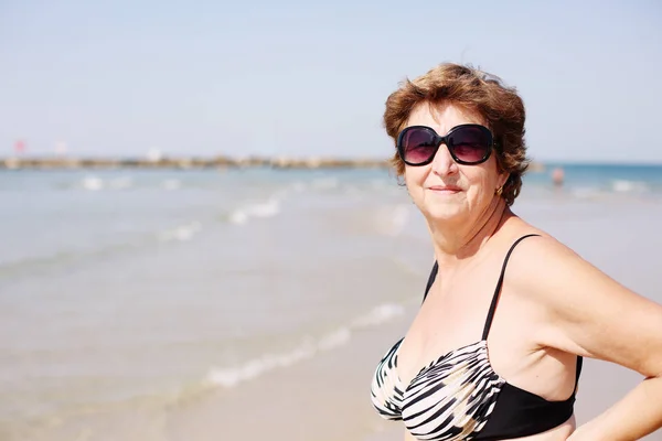 Seniorin steht am Strand — Stockfoto