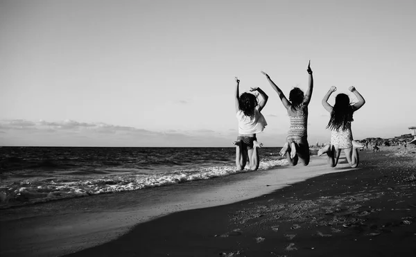 Tre flickvänner hoppning på stranden — Stockfoto