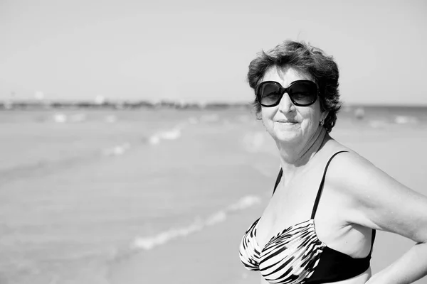 Senior mulher de pé na praia — Fotografia de Stock