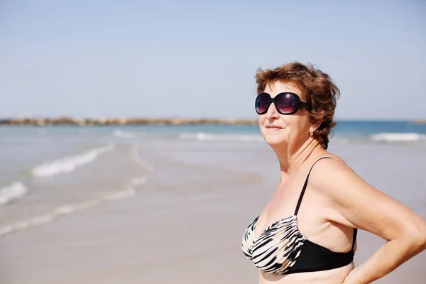 Ανώτερος γυναίκα να στέκεται στην παραλία — Φωτογραφία Αρχείου