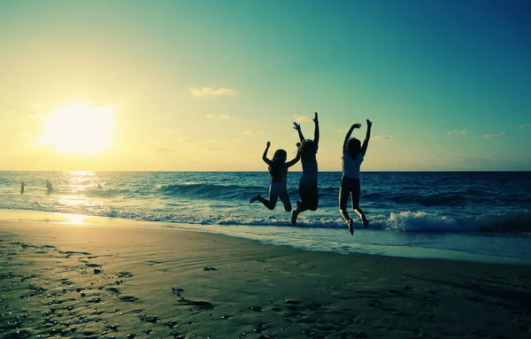Three girlfriends jumping on the beach — Stock Photo, Image