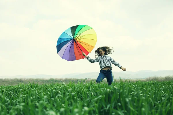 Дівчина з парасолькою стрибає в полі — стокове фото